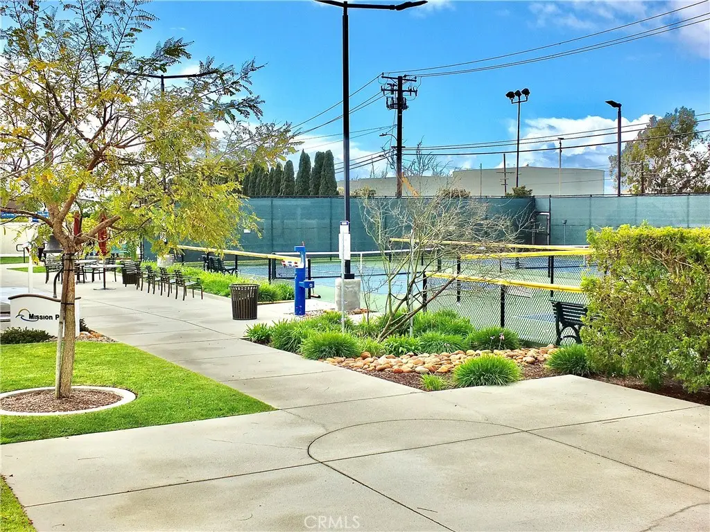 Community pathway with benches and greenery, leading to tennis courts, highlighting Leisure World Seal Beach's active lifestyle amenities.