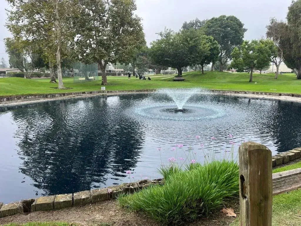 Serene pond with fountain surrounded by lush greenery and trees in Leisure World community, reflecting a peaceful outdoor environment for active adult residents.