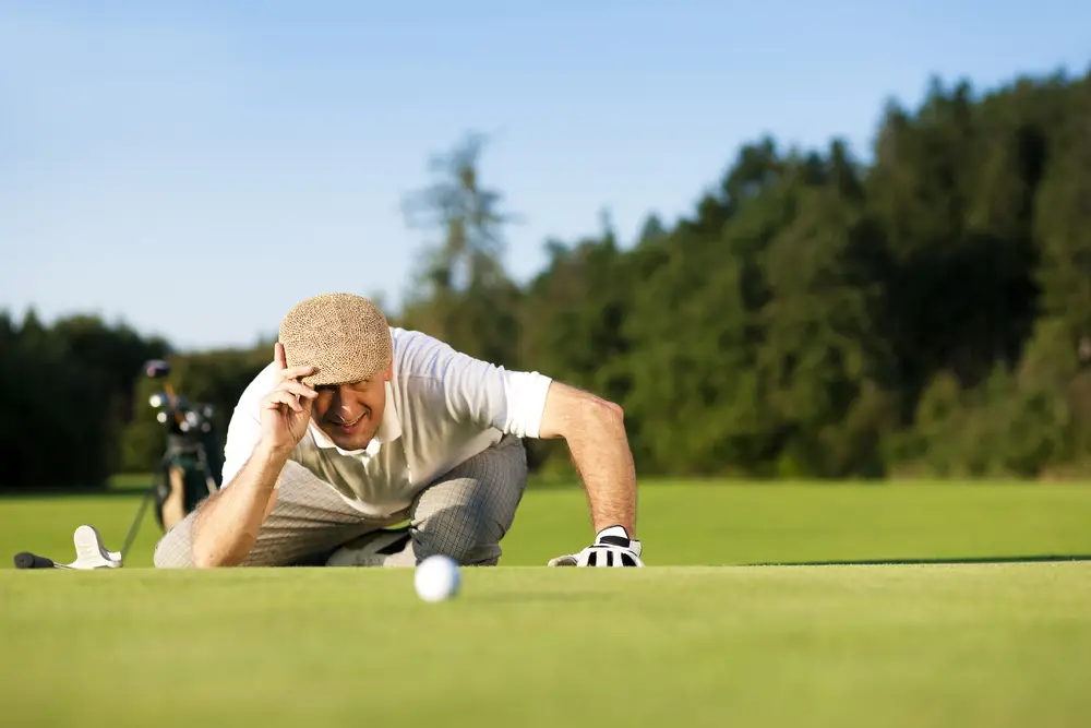 Man in golf attire analyzing a putt on a green, emphasizing active senior lifestyle in Leisure World Seal Beach community.