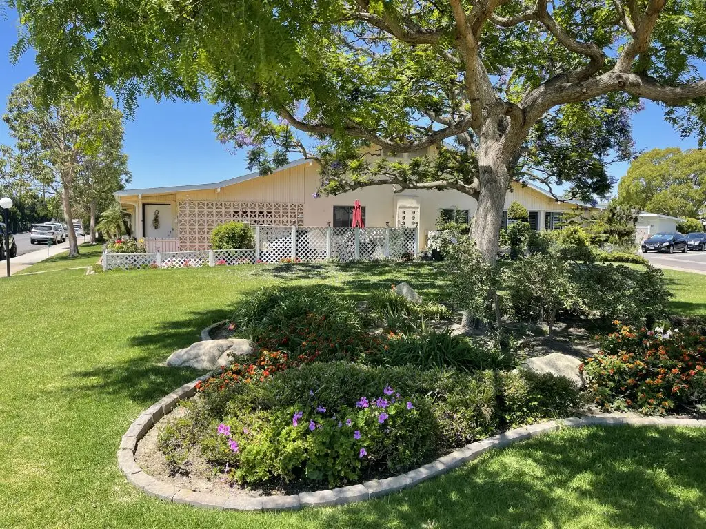 Charming home in Leisure World Seal Beach surrounded by lush gardens and vibrant flowers, showcasing a welcoming atmosphere in a 55+ retirement community.