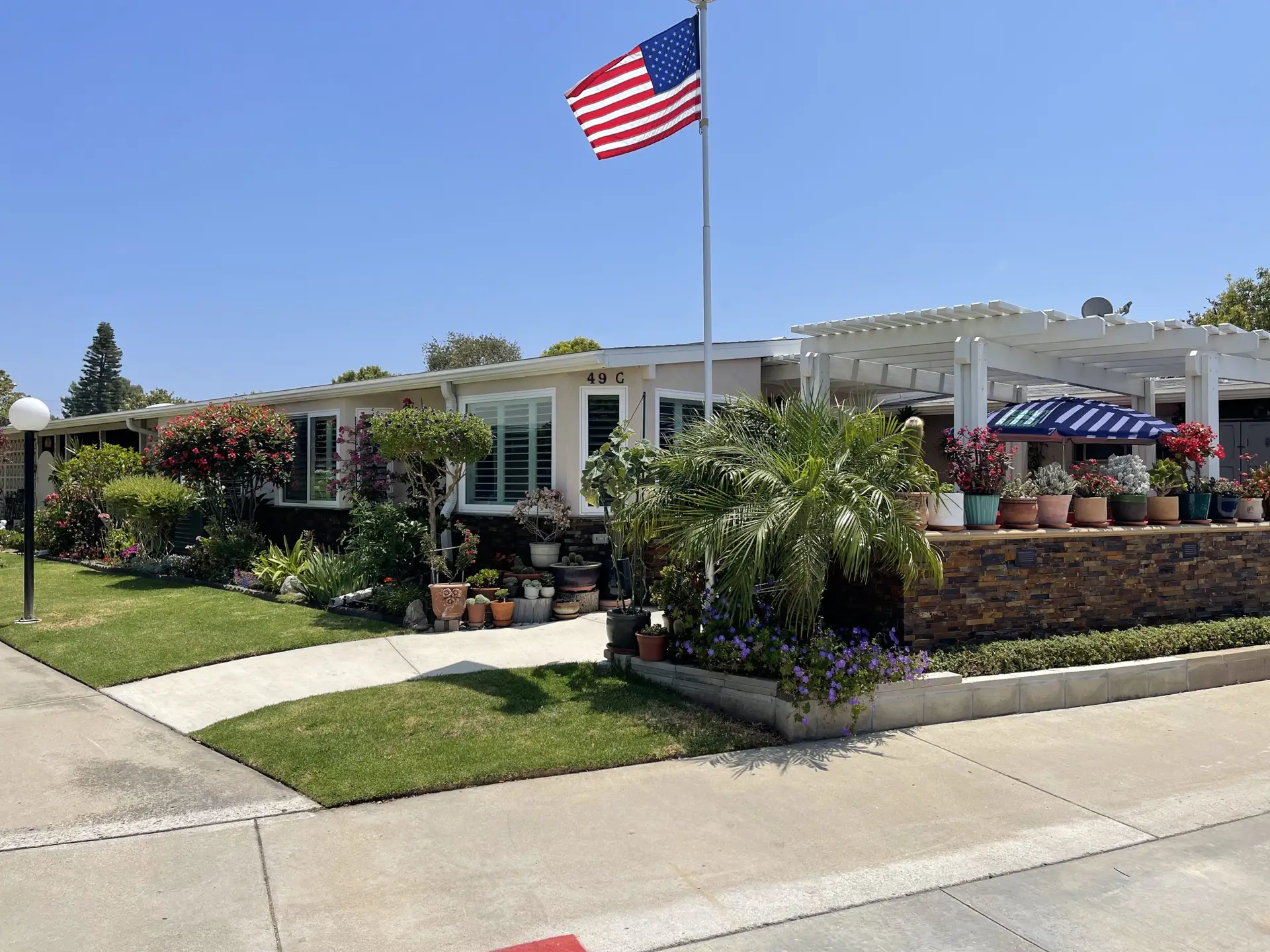 Charming Leisure World Seal Beach home with lush landscaping, American flag, and outdoor seating, showcasing affordable senior living options.