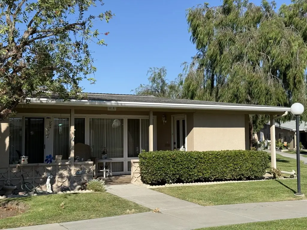 Single-story residence in Leisure World Seal Beach, featuring a landscaped front yard, large windows, and a welcoming porch, illustrating the community's appealing housing options for the 55+ demographic.