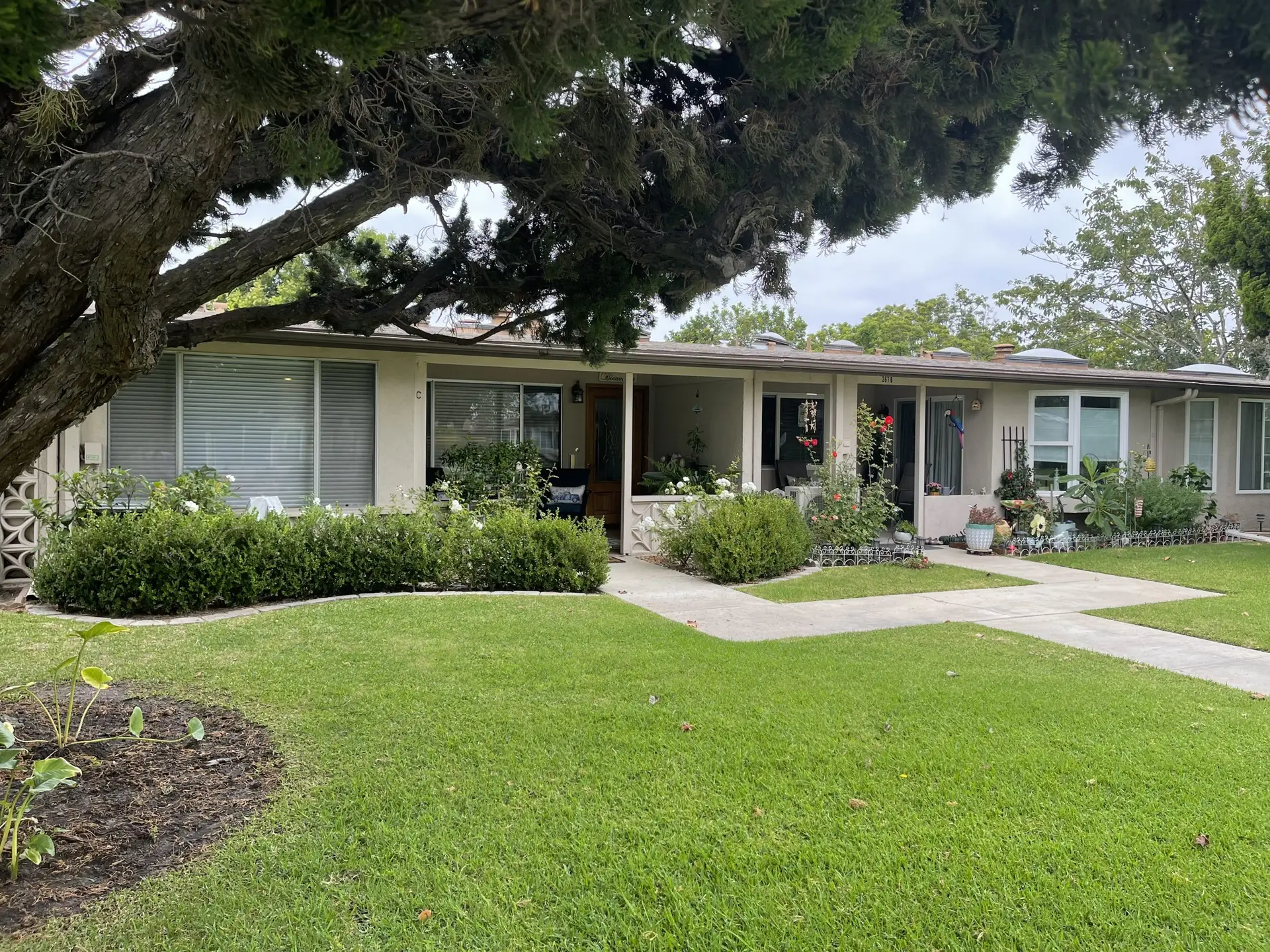 Leisure World Seal Beach home exterior with landscaped front yard, showcasing a welcoming entrance and vibrant greenery, reflecting the community's appeal for 55+ living.