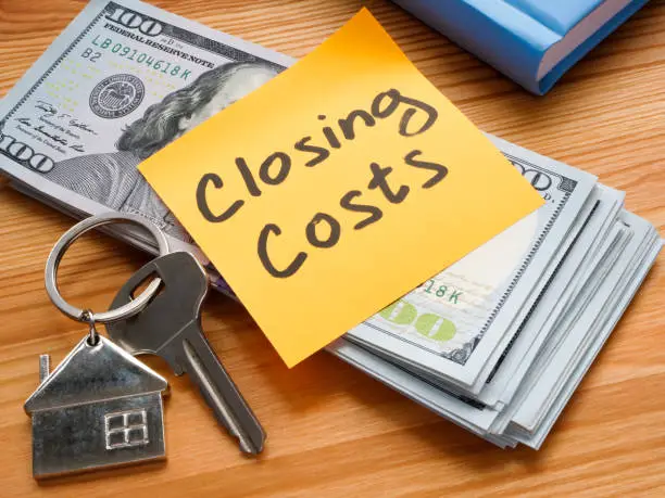 Keys with a house keychain beside a stack of cash and a sticky note labeled "Closing Costs," symbolizing financial aspects of real estate transactions in Leisure World Seal Beach.