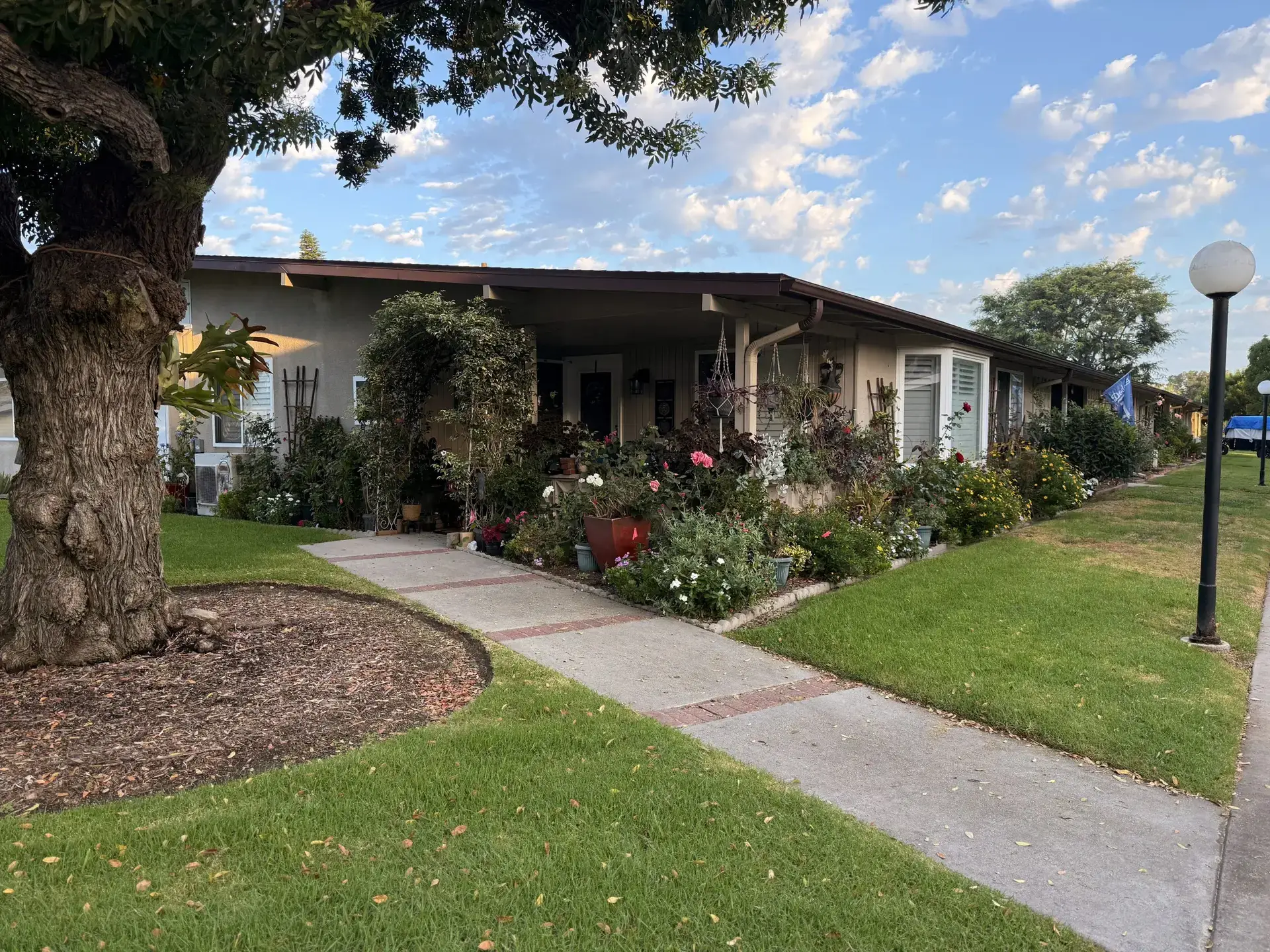 Charming Leisure World Seal Beach home exterior with landscaped garden, showcasing vibrant flowers and greenery, emphasizing community aesthetics and lifestyle.