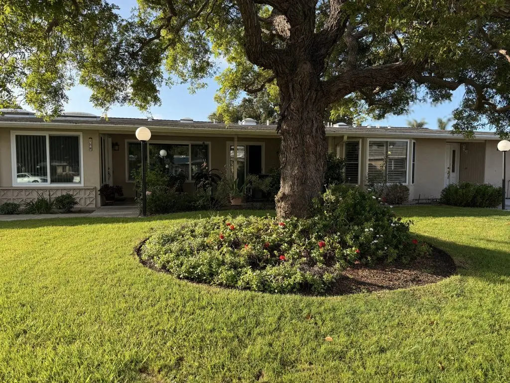 Maintenance-free residential unit in Leisure World Seal Beach, featuring landscaped gardens, mature trees, and outdoor lighting, emphasizing the tranquil living environment for the 55+ community.