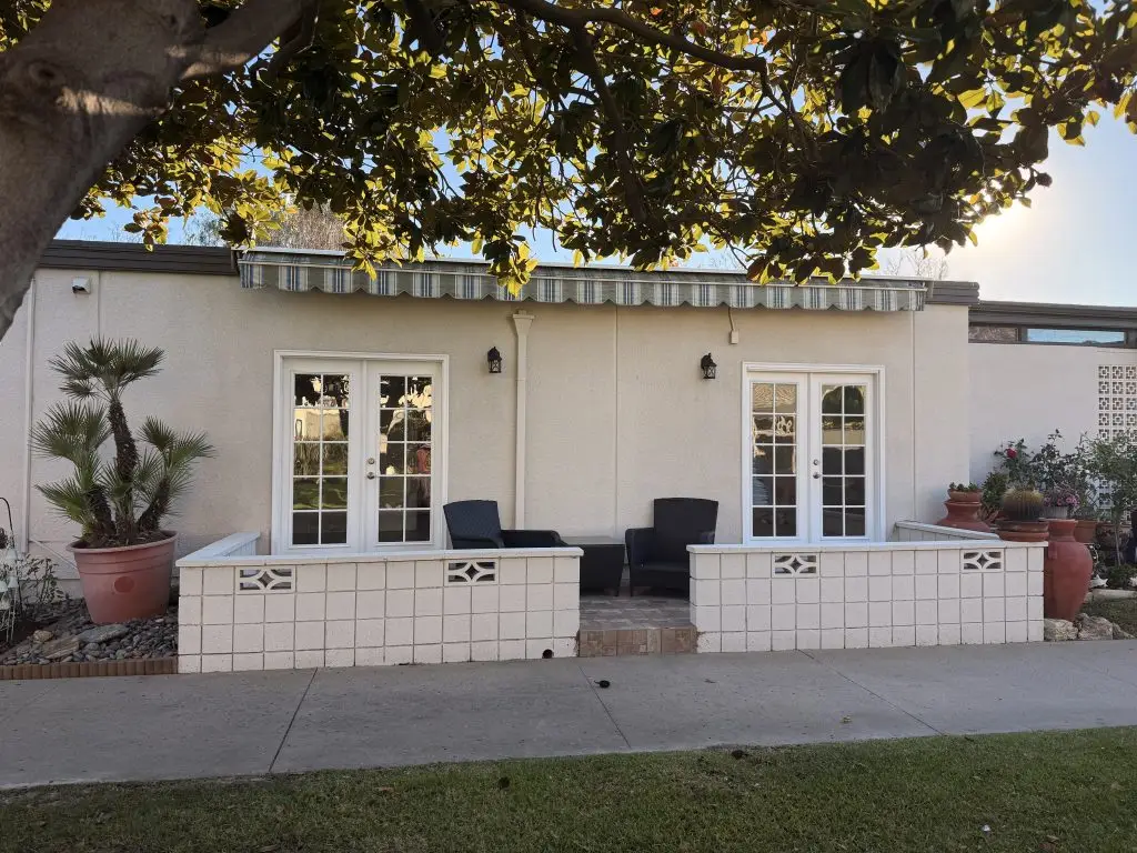 Leisure World Seal Beach exterior view featuring a cozy patio with seating, decorative planters, and a welcoming entrance, reflecting the community's serene lifestyle and real estate offerings.