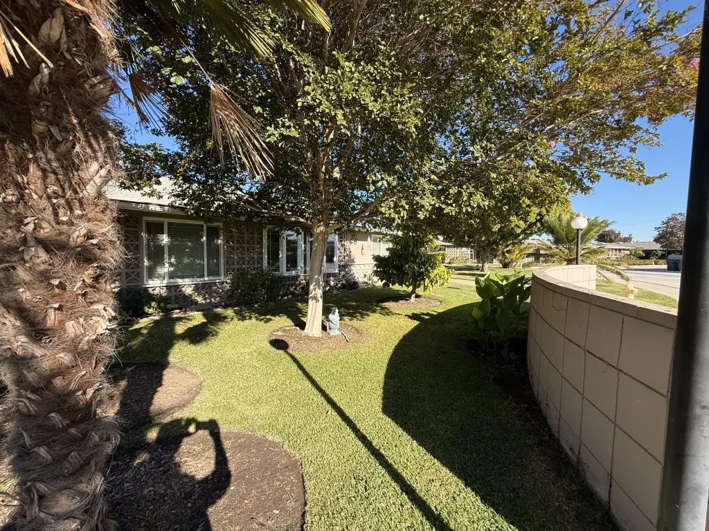 Lush landscaped garden at Leisure World Seal Beach, featuring palm trees, manicured grass, and a welcoming residential setting, promoting a vibrant lifestyle for active seniors.