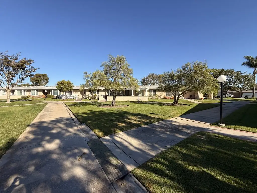 Leisure World Seal Beach community with well-maintained homes, landscaped lawns, and clear walkways, illustrating the residential setting for potential buyers and sellers in the 55+ real estate market.