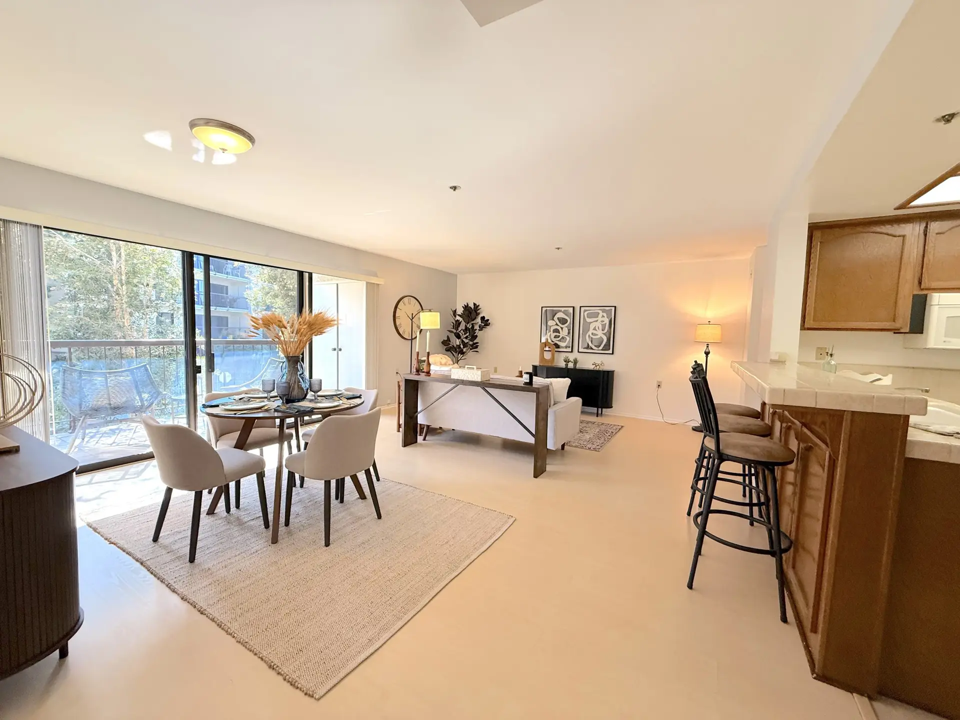 Bright and spacious living area in Leisure World Seal Beach, featuring a dining table with chairs, modern decor, and large windows showcasing outdoor views.