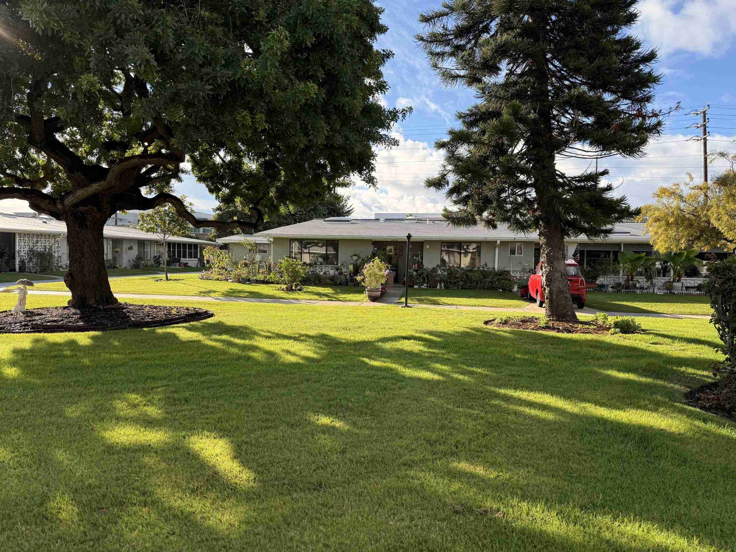 Mutual 2 Leisure World Seal Beach home with mature landscaping and a red car in the driveway.