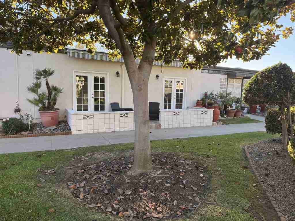 Leisure World Seal Beach home exterior with landscaped garden, showcasing a cozy patio area and decorative plants.