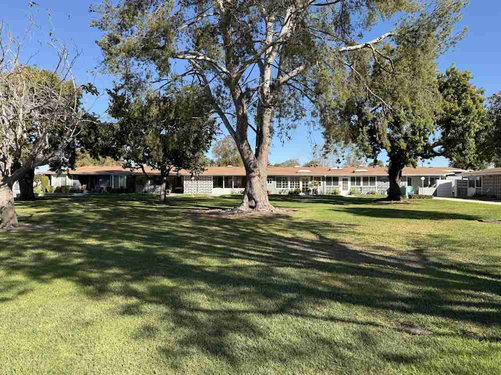 Lush green lawn and mature trees surrounding Leisure World homes in Seal Beach, CA.
