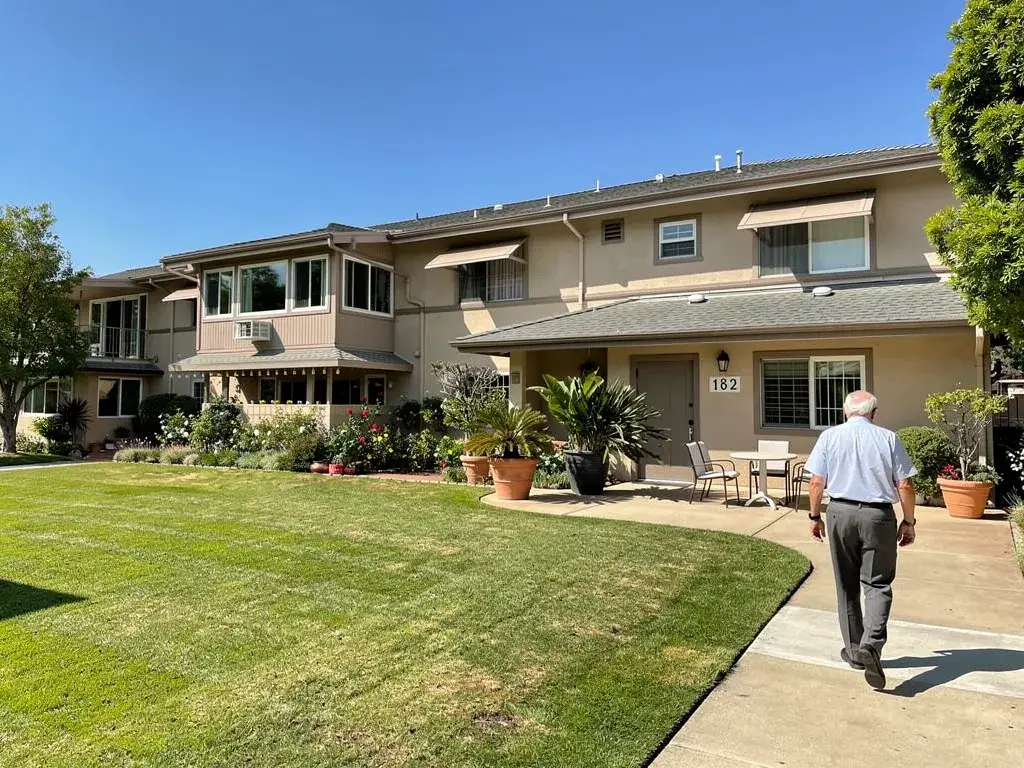 Mutual 12 Seal Beach home with well-maintained landscaping and a resident walking towards the entrance.